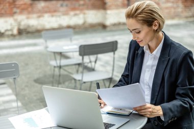 Dijital göçebe. İş kadını bir kafede masada oturuyor ve çalışıyor.