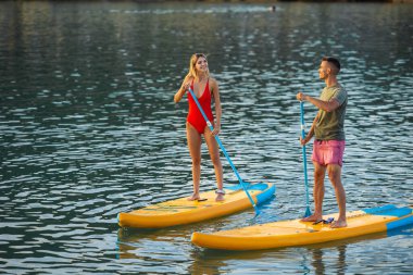 Aktif bir kadın ve erkek yaz tatilinde okyanusta sörf yapıyor..