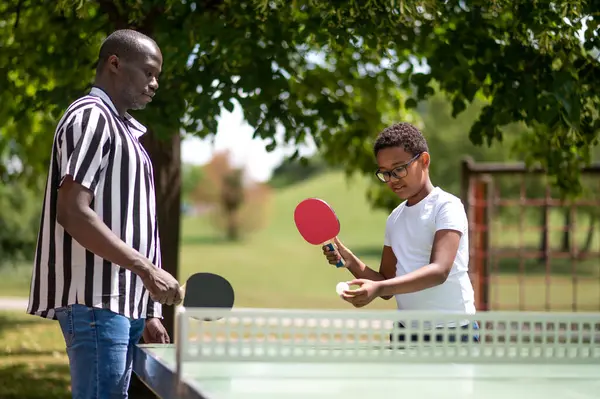 Table tennis. Dad playing table tennis with his son in the park