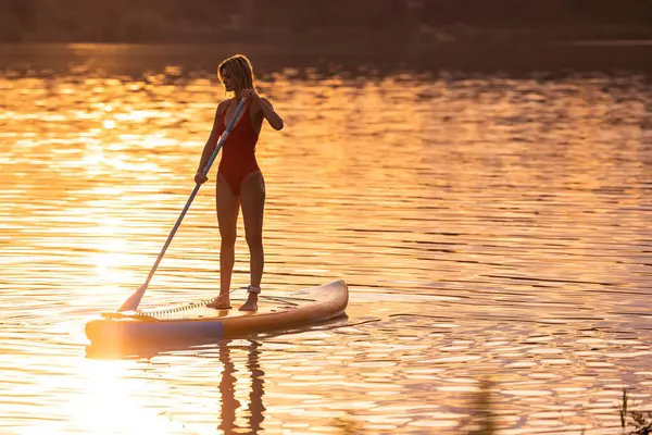 Sıska kadın silueti güneş batarken güvertede duruyor..