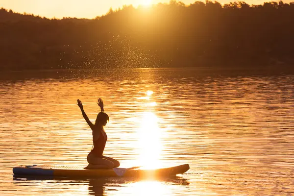 Frauensilhouette Sitzt Bei Sonnenuntergang Auf Dem Supboard Und Genießt Das — Stockfoto
