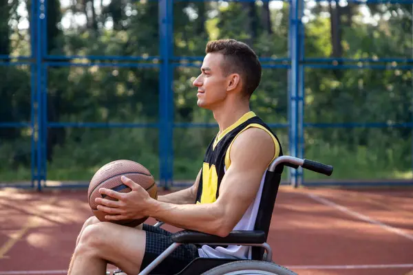 Caucasian basketball player man in wheelchair has disability playing on court, holding ball.