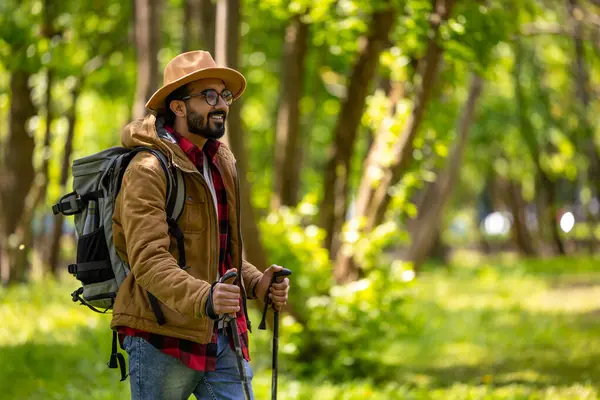 Scandinavian walk. Bearded dark-haired man in a straw hat with scandinavian sticks