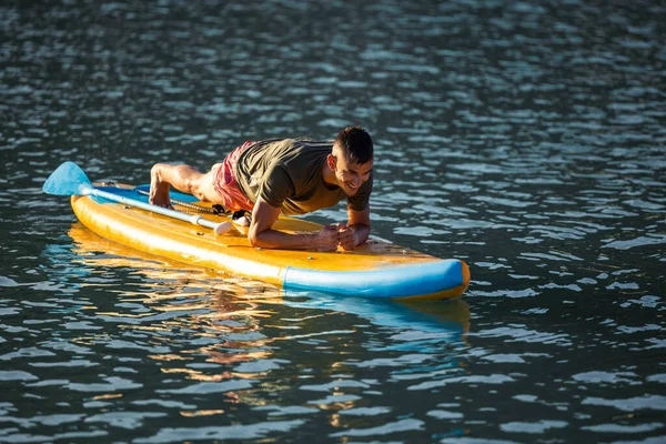 川のSupボードでヨガを練習する男 プランク — ストック写真