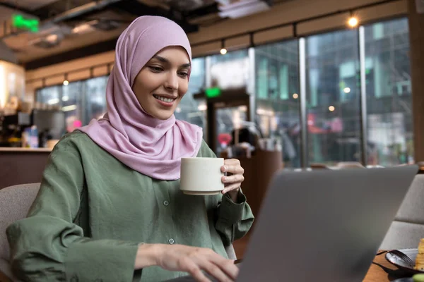 数字游牧民族 穿着头巾的年轻女人在咖啡店工作 看上去很满足 — 图库照片