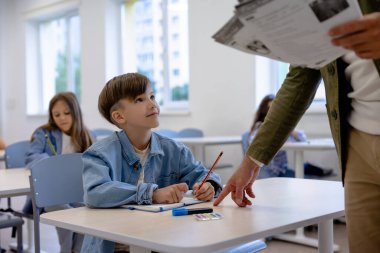 Okul dersi. Okuldaki derste öğretmeniyle çalışıyor.