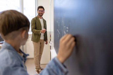 Matematik dersi. Matematik dersinde cevap veren ve tahtaya yazı yazan çocuk.