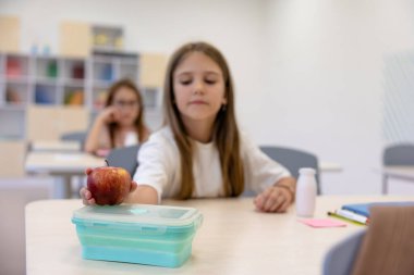 Öğle yemeği vakti. Okulda öğle yemeği yiyen uzun saçlı tatlı kız.