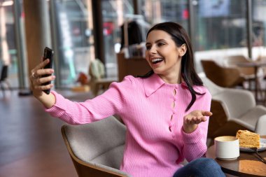 - Kafede. Pembe tişörtlü bir kız kafede oturuyor ve pozitif hissediyor.