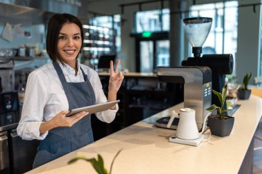 Kahve hazırlığı. Önlüklü kız kahve dükkanında masada duruyor.
