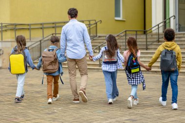 Yeni okul yılı. Erkek öğretmen yeni öğrencilerini okula götürüyor.