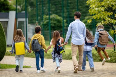 Okula dönelim. Erkek öğretmen ve öğrencileri okul bahçesinde mutlu hissediyorlar.