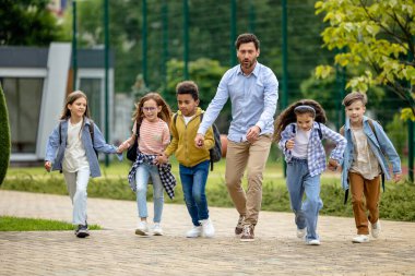 Okula dönelim. Erkek öğretmen ve öğrencileri okul bahçesinde mutlu hissediyorlar.