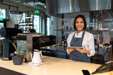 Kahve dükkanı. Kafede önlüklü, kısa saçlı, güzel bir kız.