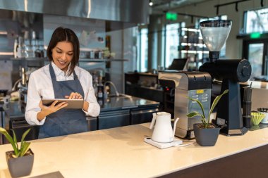 Kahve dükkanı. Kafede önlüklü, kısa saçlı, güzel bir kız.
