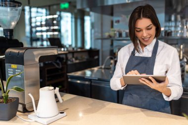 Kahve dükkanı. Kafede önlüklü, kısa saçlı, güzel bir kız.