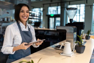 Kahve hazırlığı. Önlüklü kız kahve dükkanında masada duruyor.