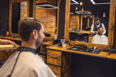 Erkek kuaför berber dükkanında müşteriye saç stili yapıyor..