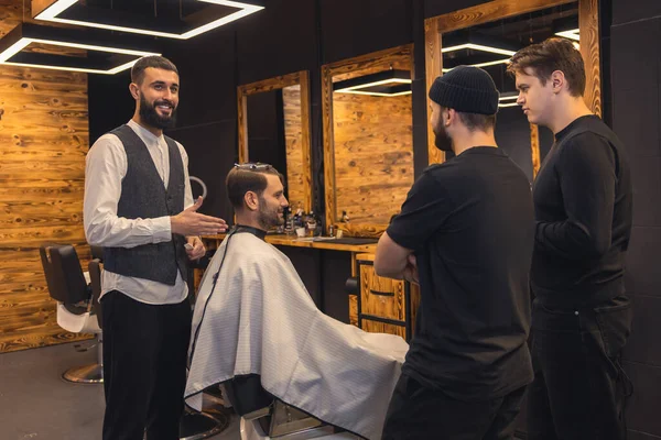 Professional barber teaches student to make mens hairstyles on model.