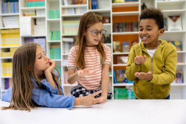 Çocuklar kütüphanede oturmuş ders bekliyorlar..