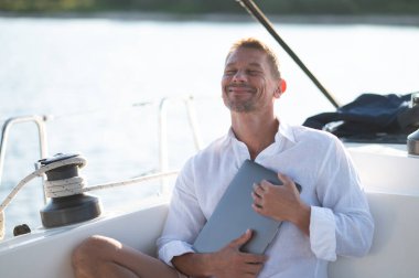 Dijital göçebe. Yat üzerinde çalışan dizüstü bilgisayarı olan başarılı olgun bir adam.