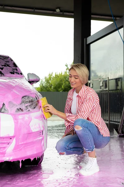 Car wash. Woman cleaning a white car the car wash