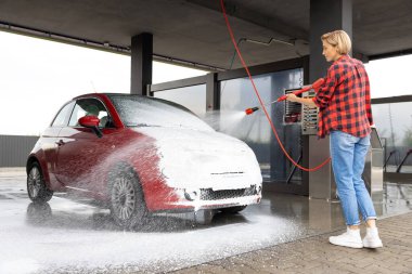 Araba servisi. Kadın oto yıkamada çalışıyor ve arabayı yıkıyor.