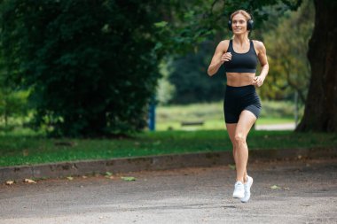 Sağlık ve sağlık. Yaz antrenmanı. Aktif yaşam tarzı. Parkta koşan sarışın atlet kadın..
