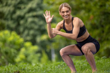Çalışıyorum. Gecekondu antrenmanı. Güzel bir kadın yaz parkında çömelme egzersizi yapıyor, birine el sallıyor..