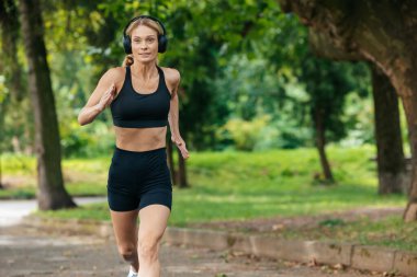 Aktif koşucu. Sportif kız. Maraton antrenmanı. Çapraz koşu. Parkta koşan sarışın atlet kadın..