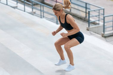 Egzersiz yapıyorum. Spor kıyafetli sarışın kadın merdivenlerden atlıyor.