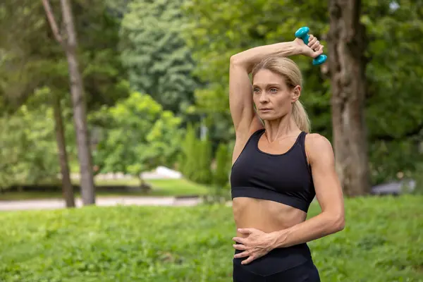 哑铃运动 三头肌运动 美丽的大自然在室外用哑铃锻炼的体态健壮的妇女在公园里有体育活动 — 图库照片