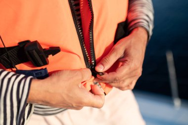 Yolculuk. Bir yatta can yeleği giyen bir adam.