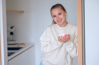 Kahve zamanı. Gülümseyen tatlı kız mutfakta kahve içiyor.