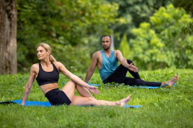 Açık havada antrenman. Yaz sporu. Konsantrasyon pratiği. Yeşil Park 'ta yoga egzersizleri yapan erkek ve kadın..