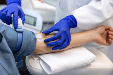 Hastanedeki hastaların kollarına damarlarına kateter yerleştirirken doktorlar damar yoluyla damar yoluyla bir erkeğin koluna iğne sokuyorlar..
