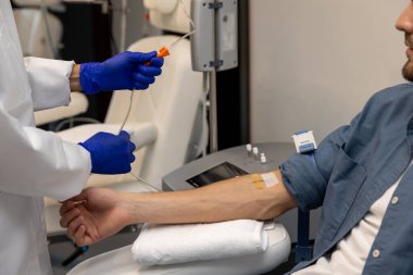 Hastanedeki hastaların kollarına damarlarına kateter yerleştirirken doktorlar damar yoluyla damar yoluyla bir erkeğin koluna iğne sokuyorlar..