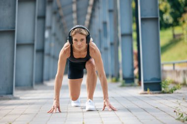 Sportif kadın koşuya hazırlanıyor ve kulaklıkla müzik dinliyor..