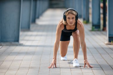 Sportif kadın koşuya hazırlanıyor ve kulaklıkla müzik dinliyor..