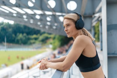 Spor antrenmanından sonra stadyumda duran kulaklıklı güzel bir kadın..