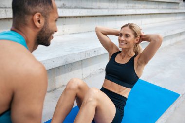 Arkadaşının desteğiyle karın kaslarını çalıştıran sportif bir kadın..