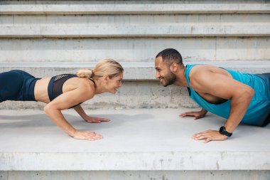 Atletik erkek ve kadın sporcu çift idman yapıyor. Açık havada birlikte hareket edin..