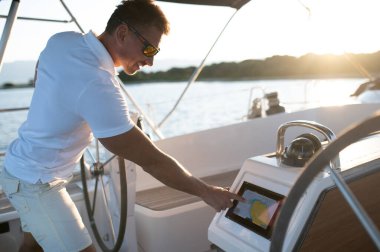 Yattaki adam. Kısa saçlı, kendine güvenen olgun bir adam yatta yelken açıyor.