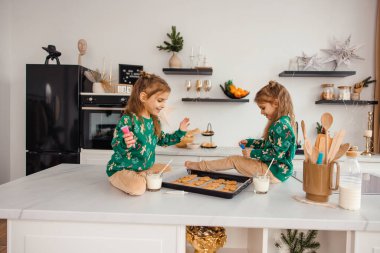 Çocuklar Noel Baba için zencefilli kurabiye hazırlıyorlar ve ilgili görünüyorlar.