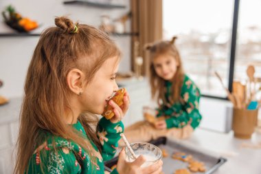 İki çocuk mutfakta kurabiye pişirirken meşgul görünüyor.