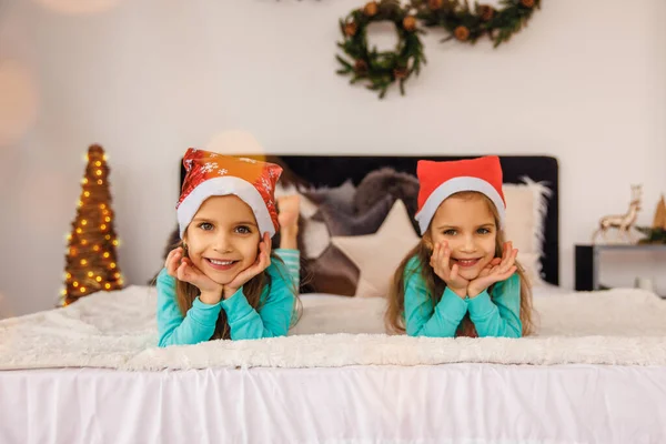Noel Şapkalı Sevimli Ikizler Yatakta Oynuyorlar — Stok fotoğraf