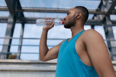 Antrenmandan sonra. İyi yapılı yakışıklı sporcu idmandan sonra su içiyor.