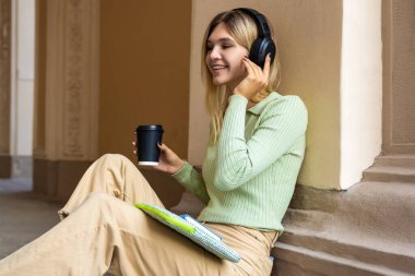 Dinliyorum. Kulaklıklı neşeli sarışın kadın.