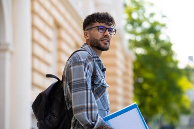 Ciddi bir adam. Sırt çantalı koyu saçlı genç adam ciddi görünüyor.