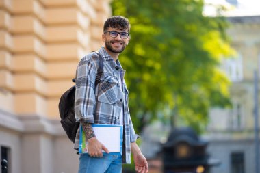 Keyfin yerinde. Kareli gömlekli gülümseyen genç adam mutlu görünüyor.